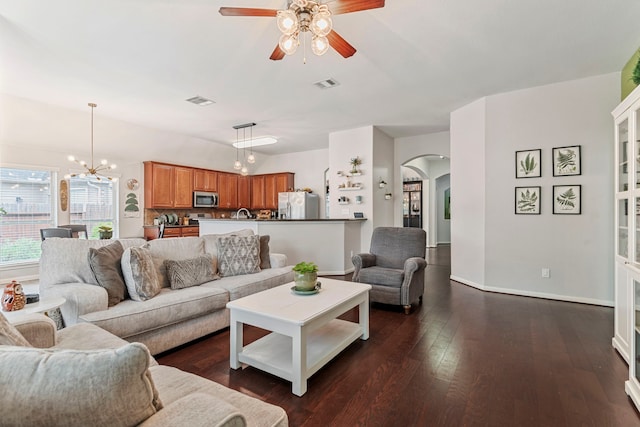 living room with dark wood-type flooring, arched walkways, visible vents, and baseboards