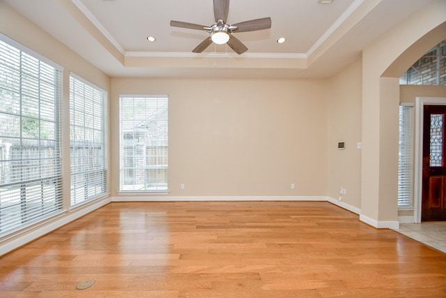 foyer entrance with crown molding, a tray ceiling, and light hardwood / wood-style flooring