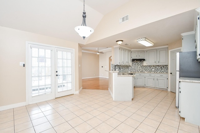 kitchen featuring lofted ceiling, light tile patterned floors, hanging light fixtures, tasteful backsplash, and kitchen peninsula