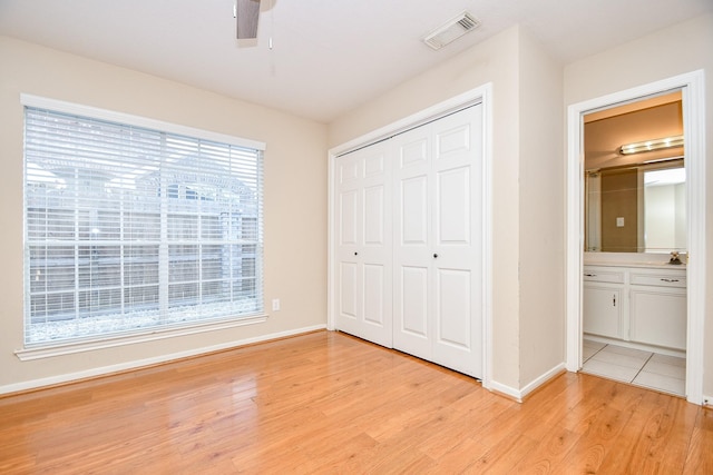 unfurnished bedroom featuring ceiling fan, sink, light wood-type flooring, and a closet