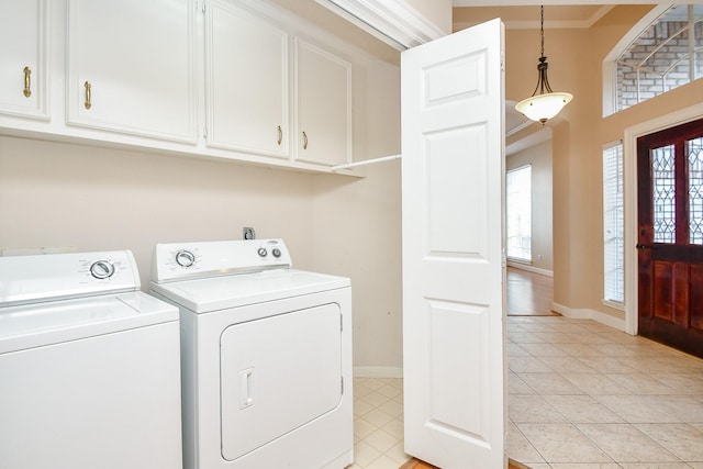 laundry room featuring cabinets, crown molding, light tile patterned floors, and washing machine and clothes dryer