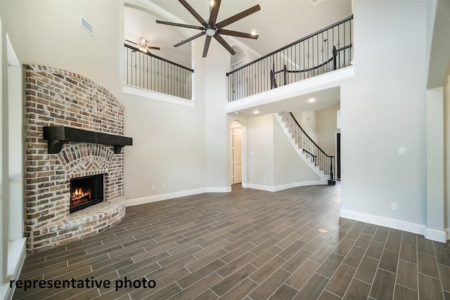 40858 Community Rd, Magnolia, TX 77354 - unfurnished living room featuring ceiling fan, a towering ceiling, a brick fireplace, baseboards, and dark wood finished floors