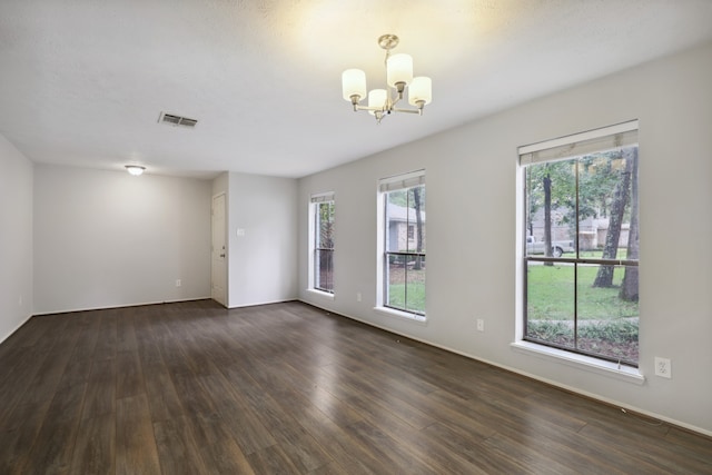 spare room with dark wood-type flooring and a chandelier