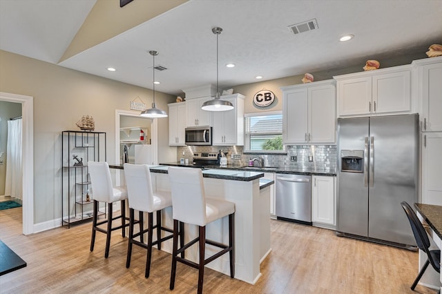 kitchen with light hardwood / wood-style floors, a center island, stainless steel appliances, hanging light fixtures, and white cabinetry