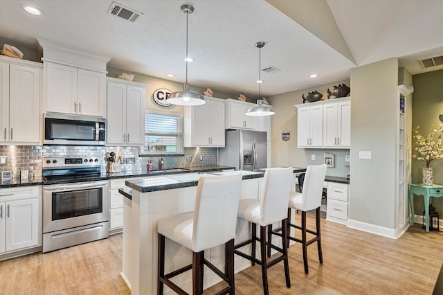 kitchen featuring white cabinets, a center island, stainless steel appliances, and light hardwood / wood-style flooring