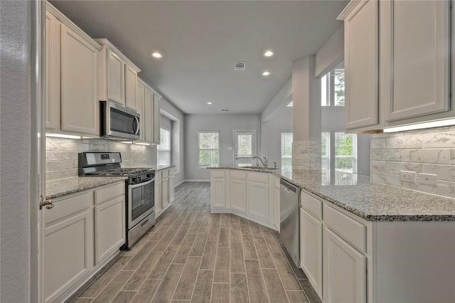 kitchen featuring white cabinetry, light wood-type flooring, appliances with stainless steel finishes, and kitchen peninsula