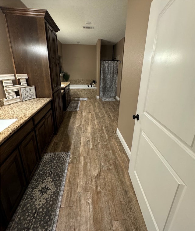 bathroom with vanity, hardwood / wood-style floors, and plus walk in shower