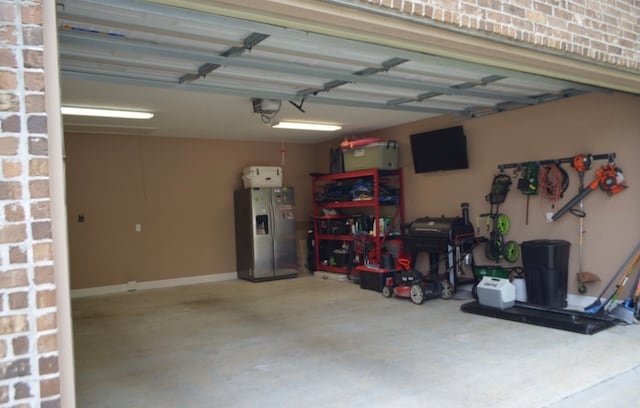 garage with stainless steel fridge and a garage door opener