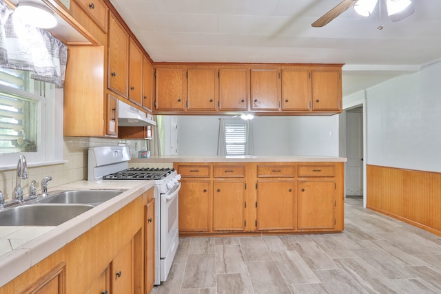 kitchen featuring white range with gas cooktop, light wood-type flooring, tile counters, sink, and ceiling fan