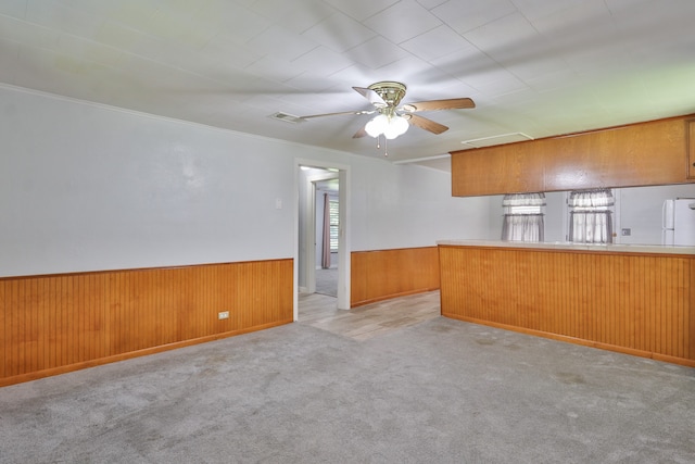 kitchen featuring plenty of natural light, ceiling fan, wooden walls, and kitchen peninsula