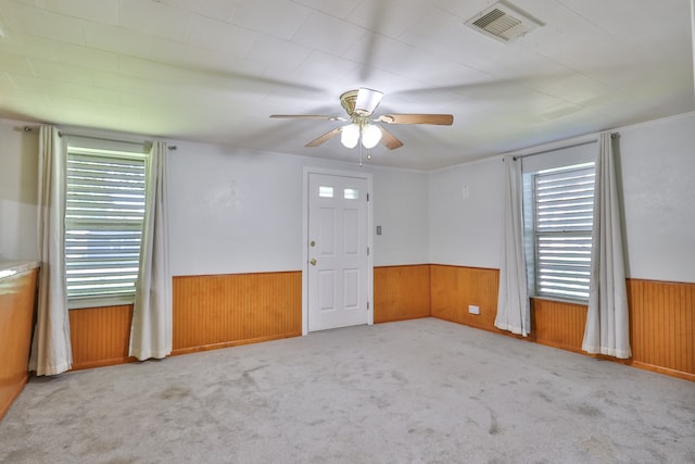 carpeted empty room featuring wood walls and ceiling fan