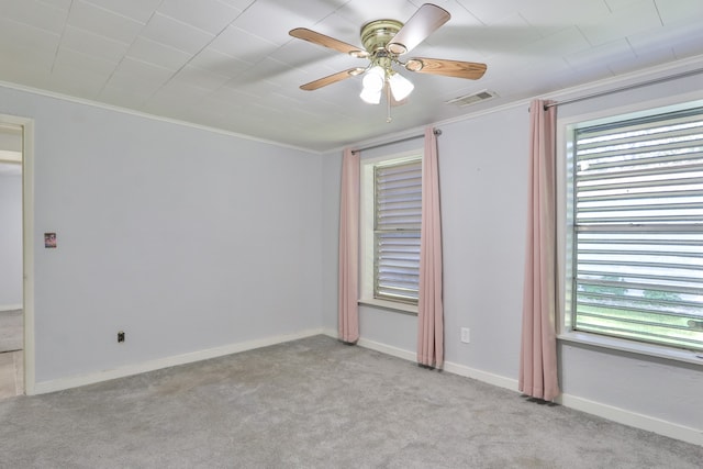 carpeted empty room featuring a healthy amount of sunlight, ceiling fan, and ornamental molding