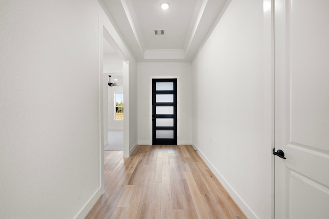 doorway with a tray ceiling, ceiling fan, and light hardwood / wood-style floors