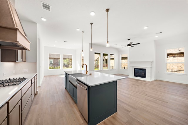 kitchen featuring hanging light fixtures, stainless steel appliances, plenty of natural light, and a kitchen island with sink