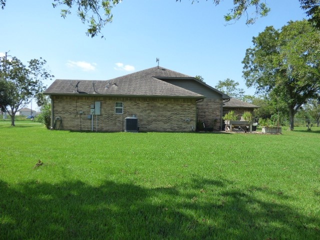 rear view of house featuring a lawn and central air condition unit