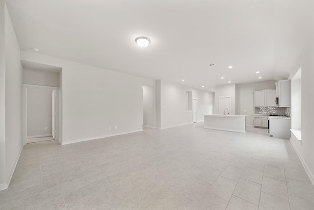 unfurnished living room with sink and light tile patterned floors