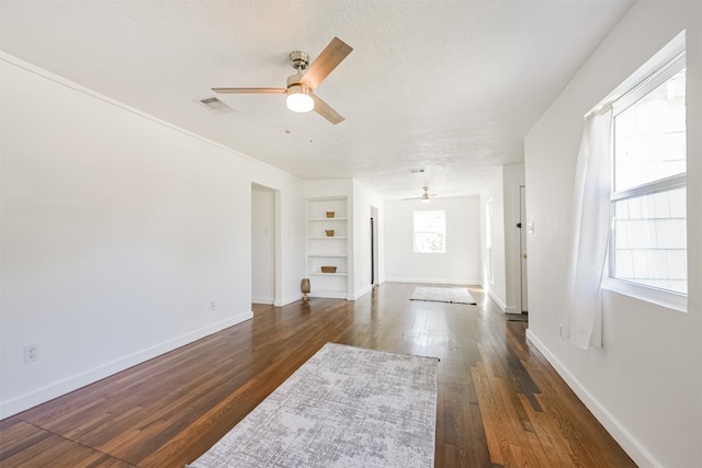 living room with dark wood-type flooring, built in features, and ceiling fan