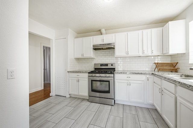 kitchen featuring sink, backsplash, a textured ceiling, white cabinetry, and stainless steel range with gas cooktop