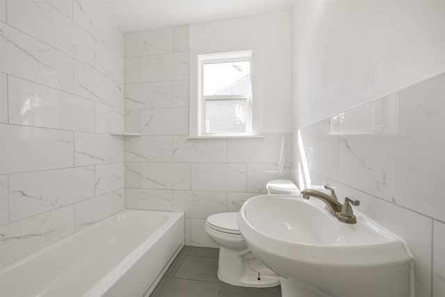 bathroom featuring toilet, tile patterned flooring, sink, tile walls, and a bath