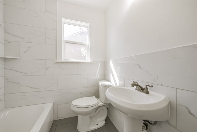 bathroom featuring tile walls, sink, toilet, and a washtub