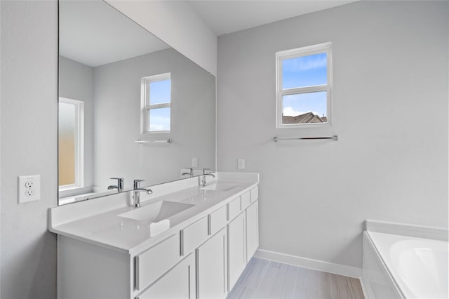 bathroom featuring a bathing tub, vanity, and a healthy amount of sunlight