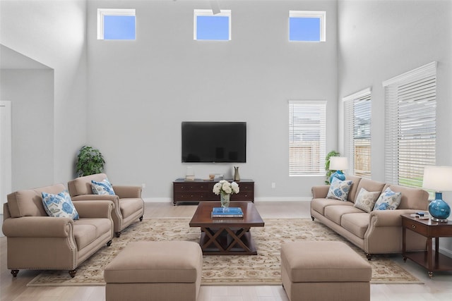 living area featuring a high ceiling, baseboards, and a wealth of natural light