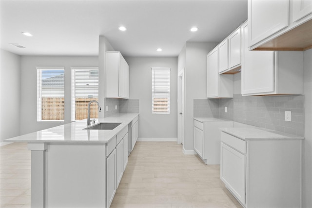 kitchen featuring a sink, visible vents, white cabinetry, baseboards, and light countertops