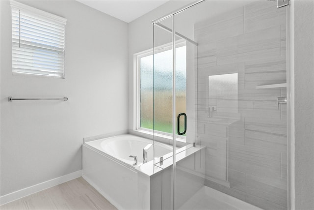 bathroom with a shower stall, a bath, and baseboards