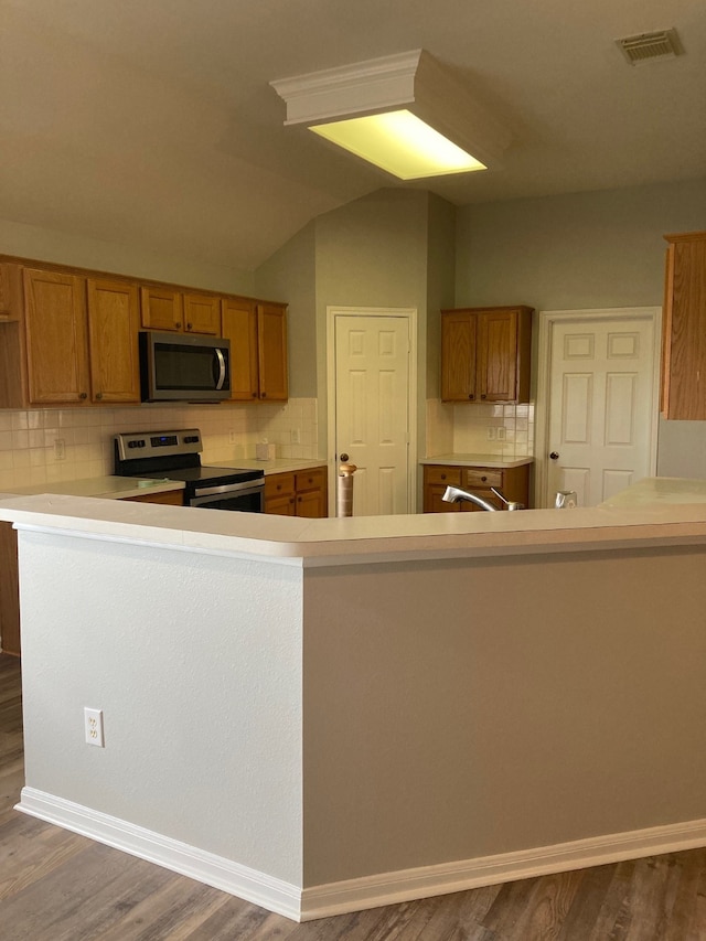 kitchen featuring lofted ceiling, backsplash, appliances with stainless steel finishes, and dark hardwood / wood-style floors