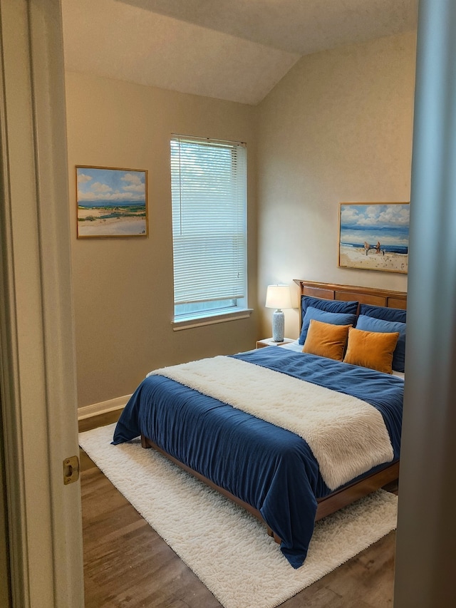 bedroom with lofted ceiling and dark hardwood / wood-style floors