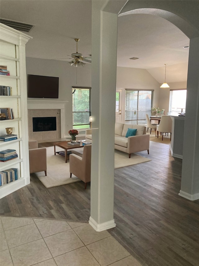 living room featuring hardwood / wood-style floors, ceiling fan, a tile fireplace, and a healthy amount of sunlight