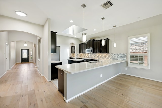 kitchen with pendant lighting, tasteful backsplash, sink, kitchen peninsula, and light wood-type flooring