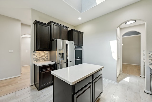 kitchen with a kitchen island, tasteful backsplash, appliances with stainless steel finishes, and light hardwood / wood-style floors