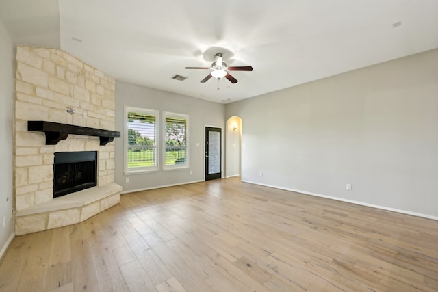 unfurnished living room with a stone fireplace, ceiling fan, and light wood-type flooring