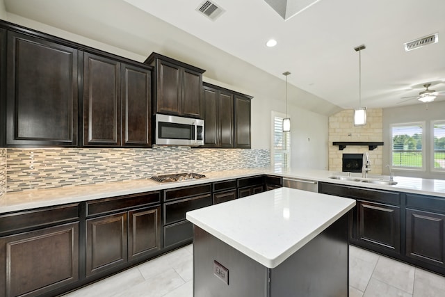 kitchen featuring a center island, kitchen peninsula, pendant lighting, stainless steel appliances, and decorative backsplash