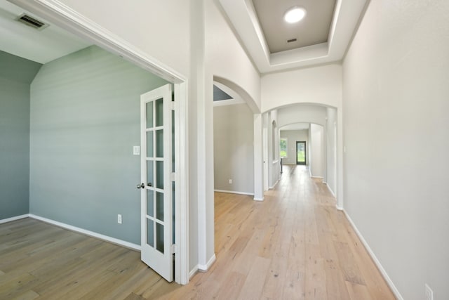 hall featuring light hardwood / wood-style floors and a tray ceiling