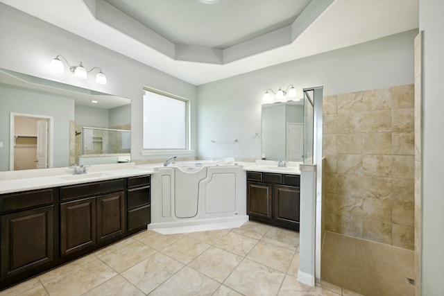 bathroom with vanity, tile patterned flooring, a tray ceiling, and tiled shower