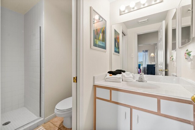 bathroom featuring a shower with door, vanity, toilet, and tile patterned flooring