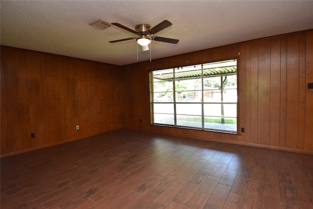 spare room with wood walls, ceiling fan, dark hardwood / wood-style floors, and a textured ceiling