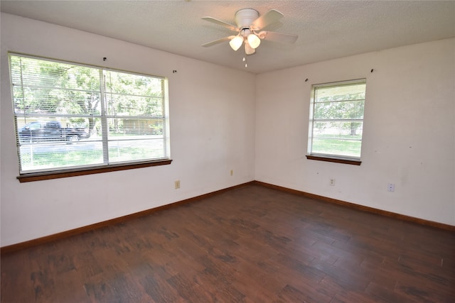 spare room featuring ceiling fan, a textured ceiling, dark hardwood / wood-style floors, and a wealth of natural light