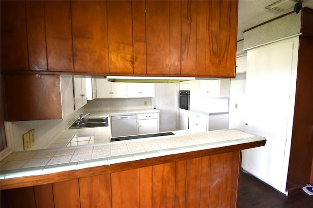 kitchen with sink, dark hardwood / wood-style floors, tile counters, and black appliances