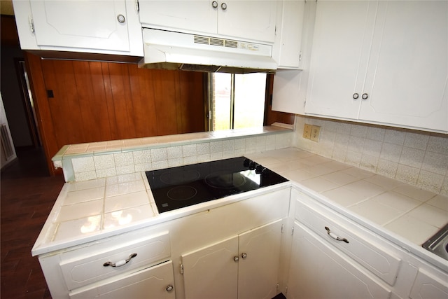 kitchen with white cabinets, black electric cooktop, tile counters, dark hardwood / wood-style flooring, and decorative backsplash