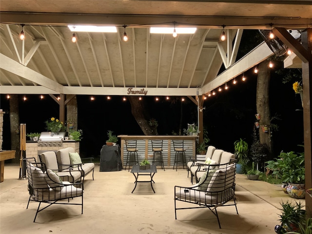 patio at night with exterior bar and area for grilling