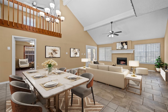 dining space featuring a healthy amount of sunlight, beamed ceiling, ceiling fan with notable chandelier, and a fireplace