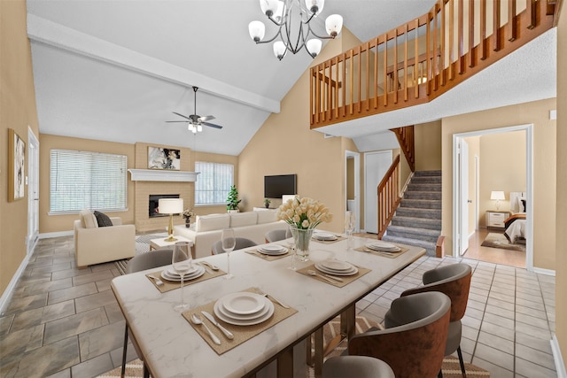 dining area featuring a fireplace, beamed ceiling, ceiling fan with notable chandelier, and light tile patterned flooring