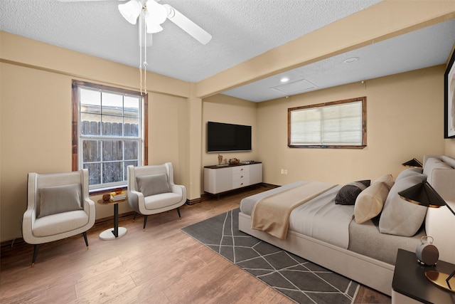 bedroom with a textured ceiling, ceiling fan, and dark hardwood / wood-style floors