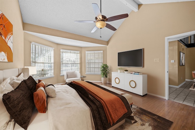 bedroom with lofted ceiling with beams, a textured ceiling, ceiling fan, and light hardwood / wood-style floors