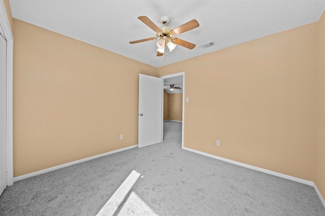 carpeted spare room with a textured ceiling and ceiling fan