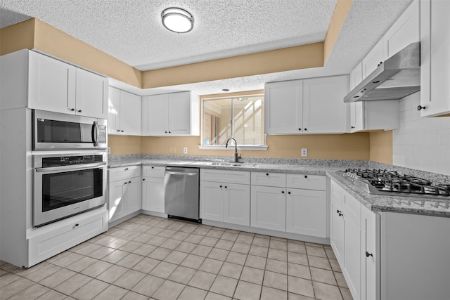 kitchen with light stone countertops, light tile patterned floors, appliances with stainless steel finishes, sink, and white cabinets