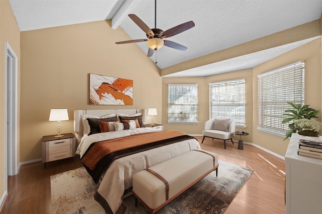 bedroom featuring a textured ceiling, ceiling fan, wood-type flooring, and vaulted ceiling with beams